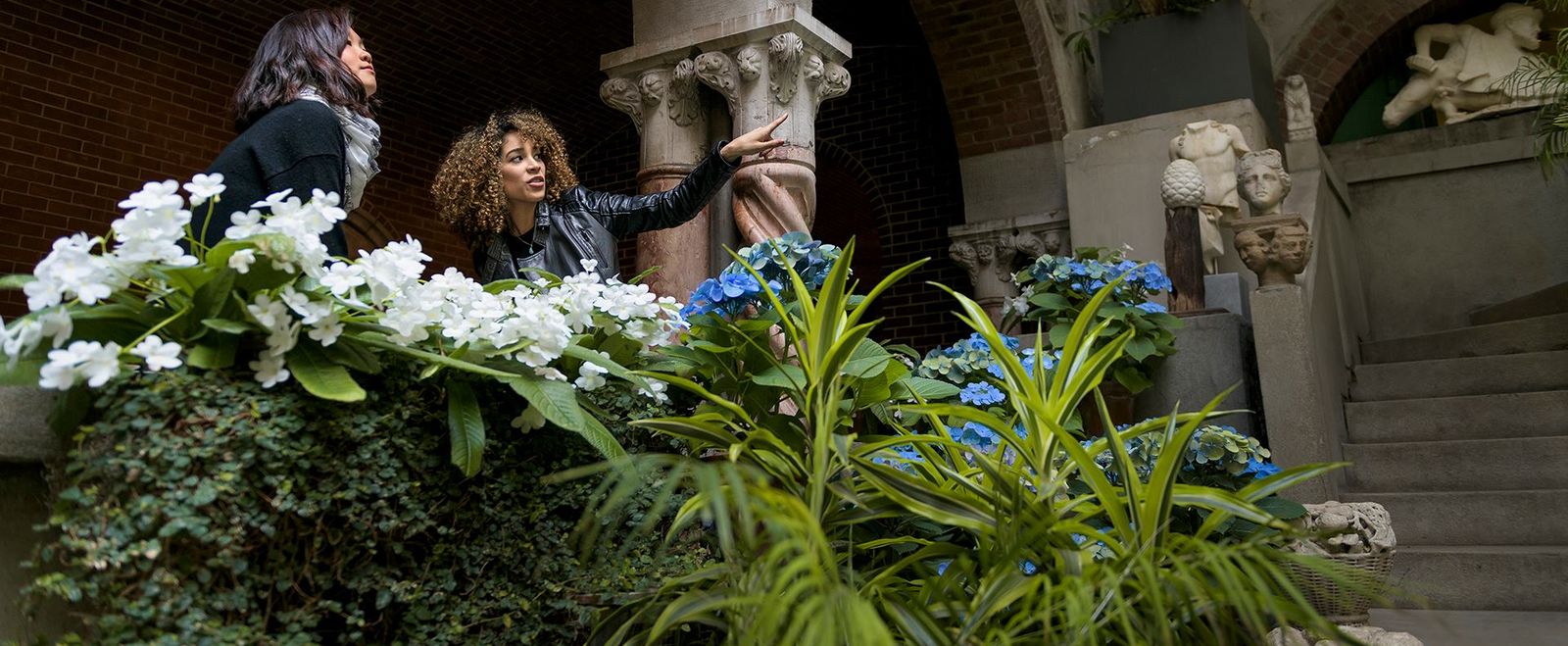 Two women point and talk at the Isabella Stewart Gardner Museum.